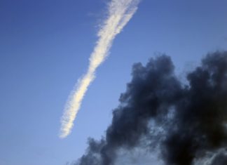 Foto, Kondensstreifen und dunkle Wolken vor klarem Himmel