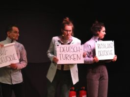 Schauspieler*innen aus "Unterscheidet euch!" auf der Bühne halten Schilder in der Hand, auf der unterschiedliche Begriffe zur Sortierung bzw. Zuordnung stehen.