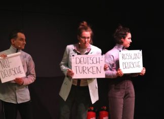 Schauspieler*innen aus "Unterscheidet euch!" auf der Bühne halten Schilder in der Hand, auf der unterschiedliche Begriffe zur Sortierung bzw. Zuordnung stehen.
