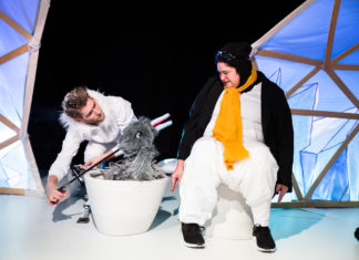 Ein Puppenspieler mit einem Plüschvogel und eine Schauspielerin als Pinguin verkleidet