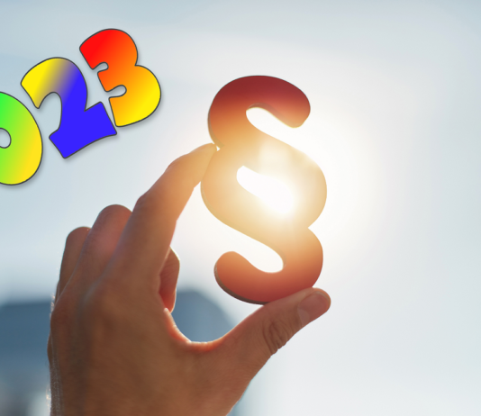 Hand hält Paragraphen Symbol in Sonne - und 2023