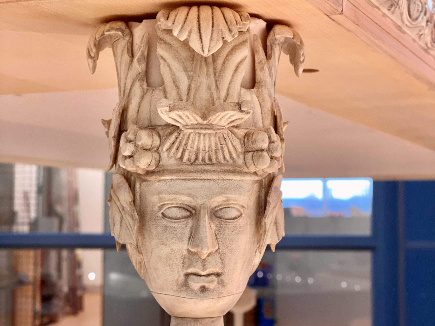 Das Foto zeigt als Detail eines rekonstruierten Totenbettes mit Knochenschnitzerei. Auf einem fein ausgearbeiteten Kopf thront eine Krone aus floralen Motiven.