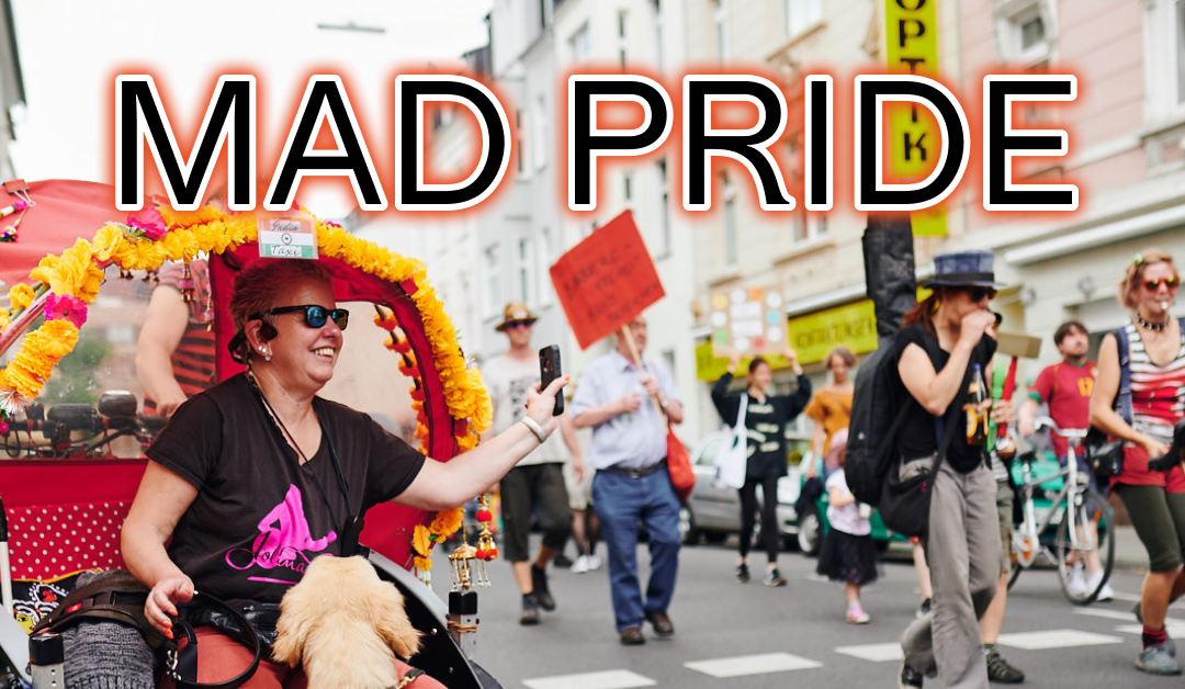 Bild einer Demonstration. Vorne sitzt eine Frau mit ihrem Hund in einer Rikscha. Hinten sieht man buntes Treiben. Es steht folgender Schriftzug über dem Bild: MAD PRIDE Mo, 20.5. 14:00, Neptunplatz Köln Ehrenfeld