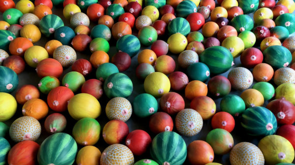 Foto: eine Ansammlung von roten, gelben und grünen runden Früchten und Melonen aus Gips;