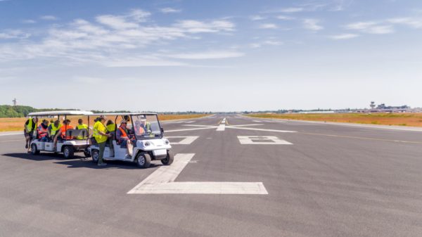 Ein Elektrocar mit Menschen in Warnwesten steht auf der Landebahn des ehemaligen Flughafens Tegel.