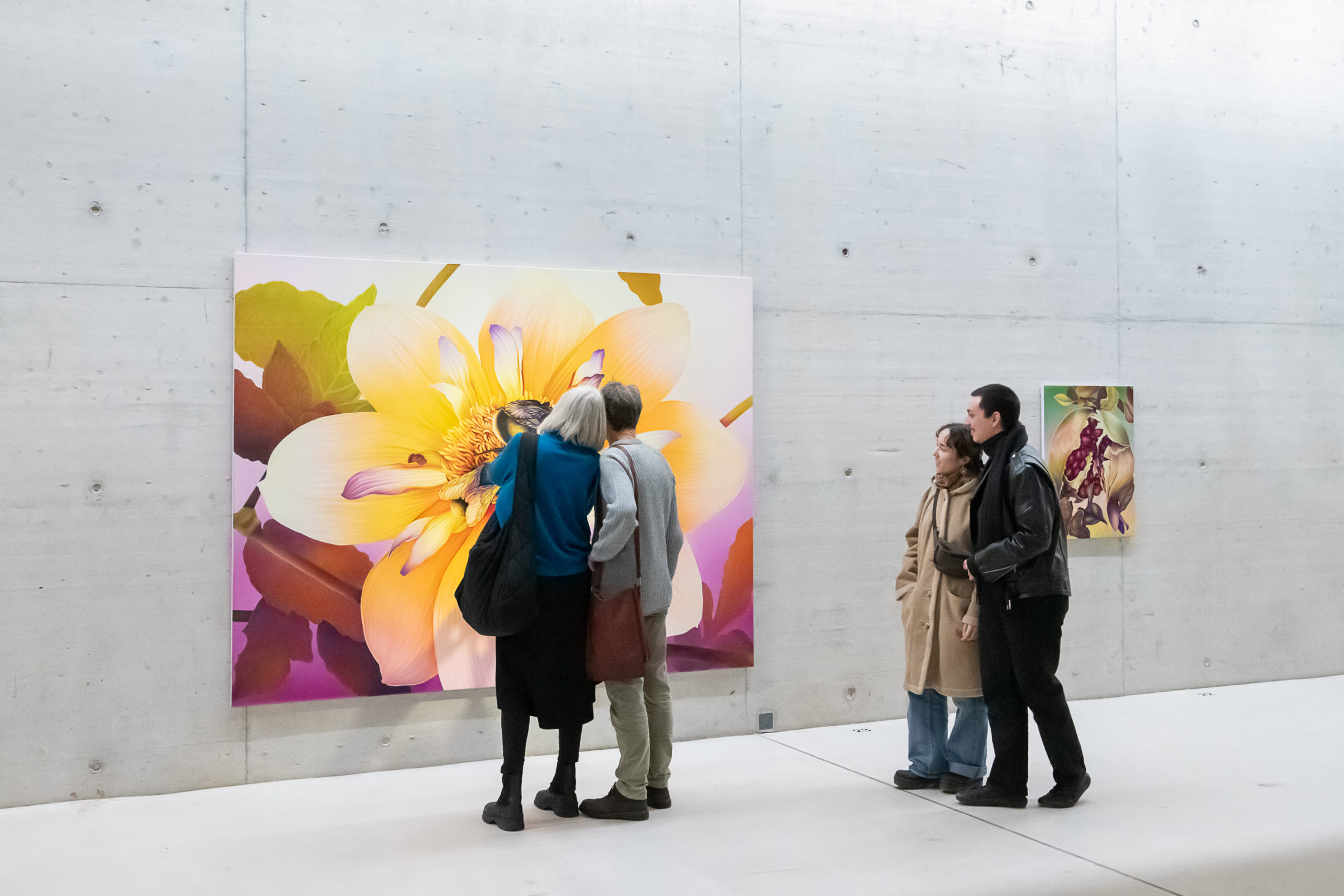 Vier Menschen stehen vor einer großen, bunten Malerei, die eine Blume zeigt.