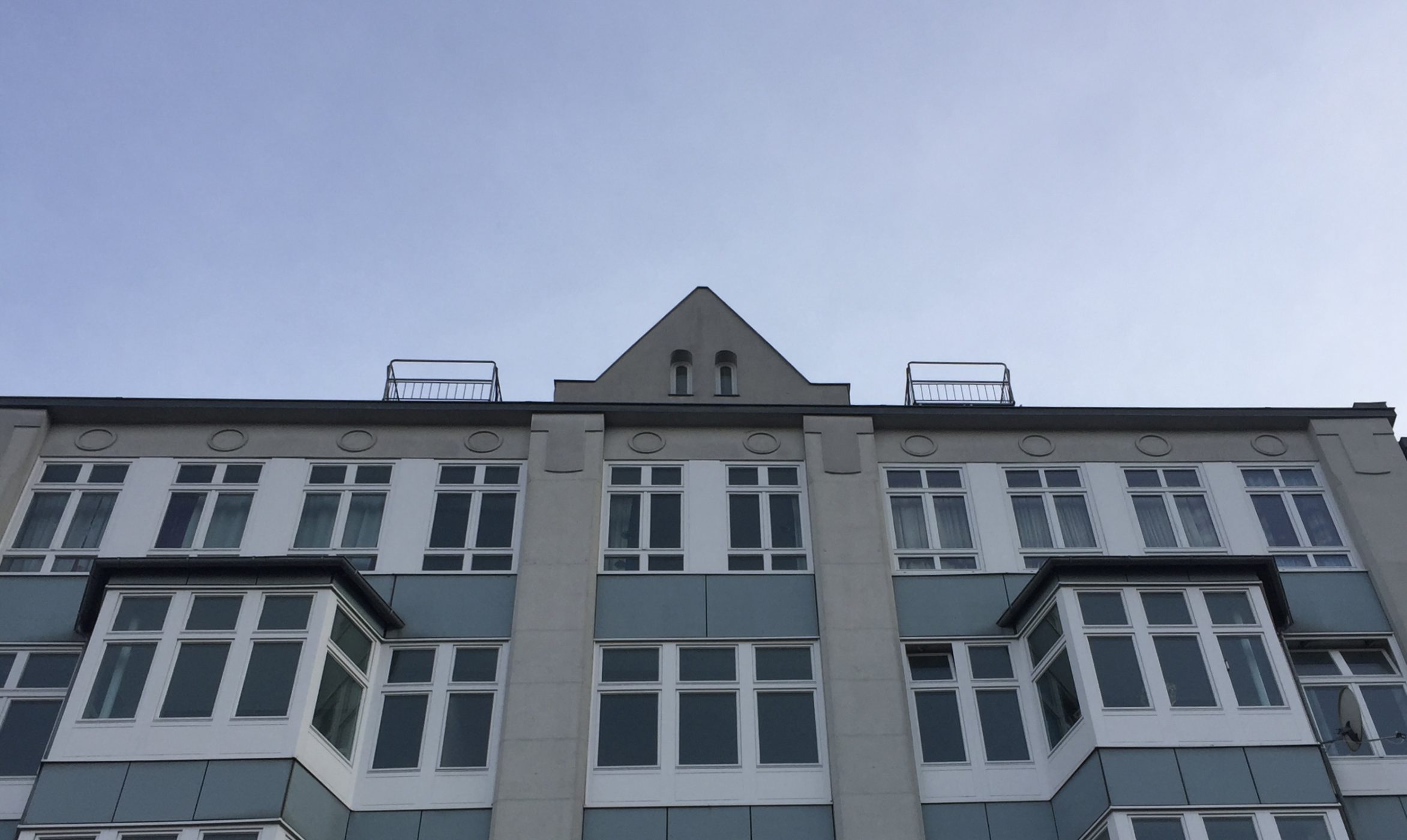 Blick auf das obere Stockwerk der Friedrichstraße 12 und den blauen Himmel dahinter.