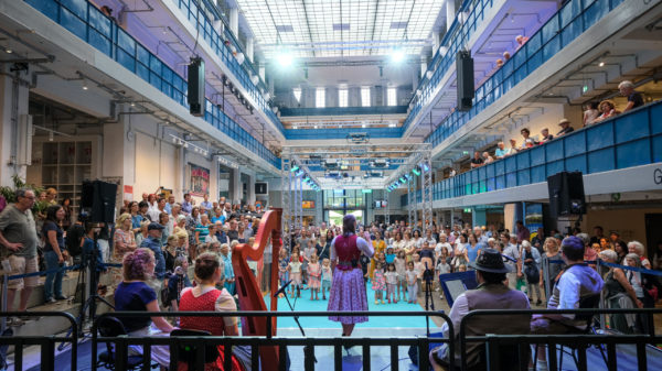 Bei dem Kultur-Sommerfest Wolke 8 stehen Volksmusiker*innen auf der Bühne in der gut gefüllten Halle E.