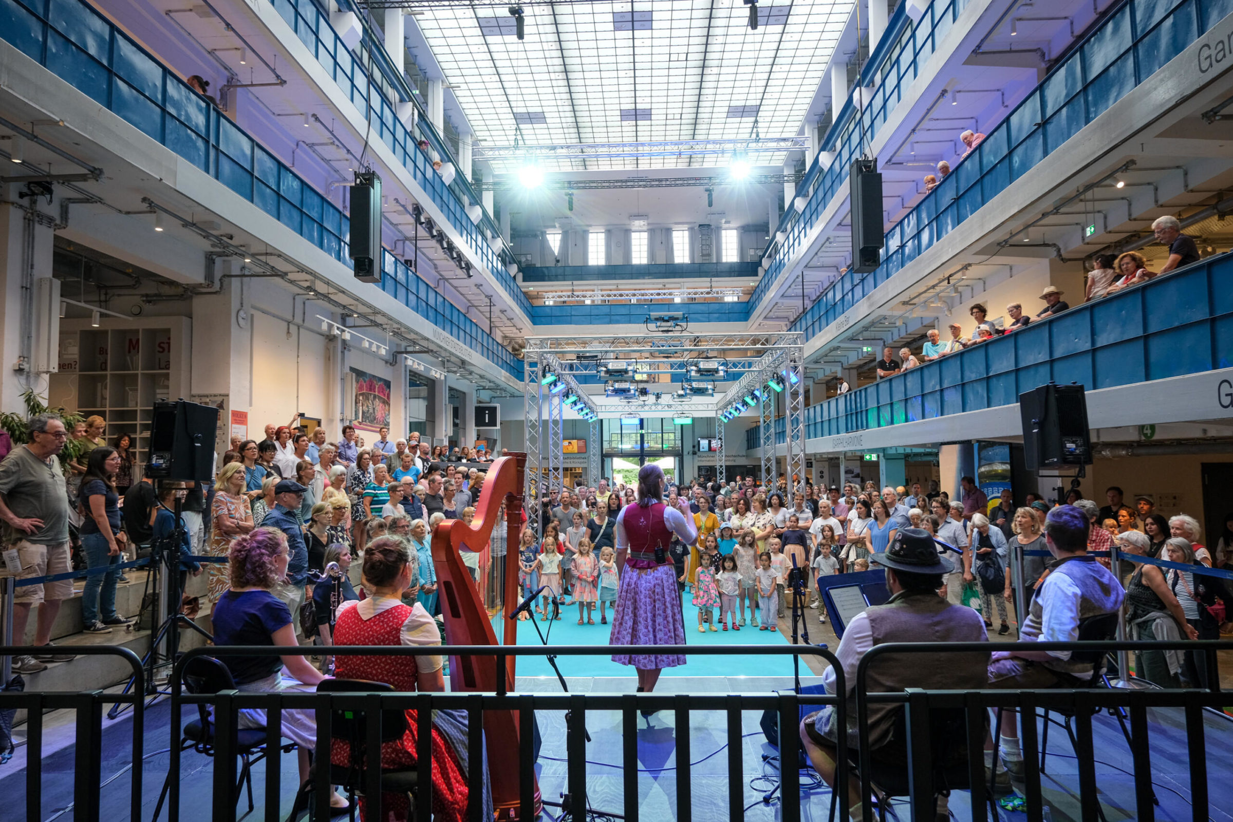 Bei dem Kultur-Sommerfest Wolke 8 stehen Volksmusiker*innen auf der Bühne in der gut gefüllten Halle E.