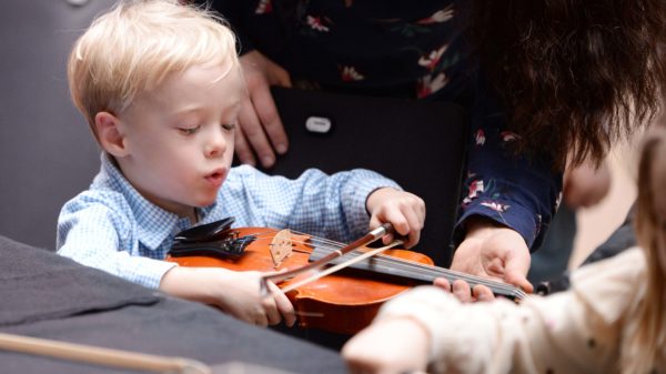 Ein Kind streicht auf einer Geige.