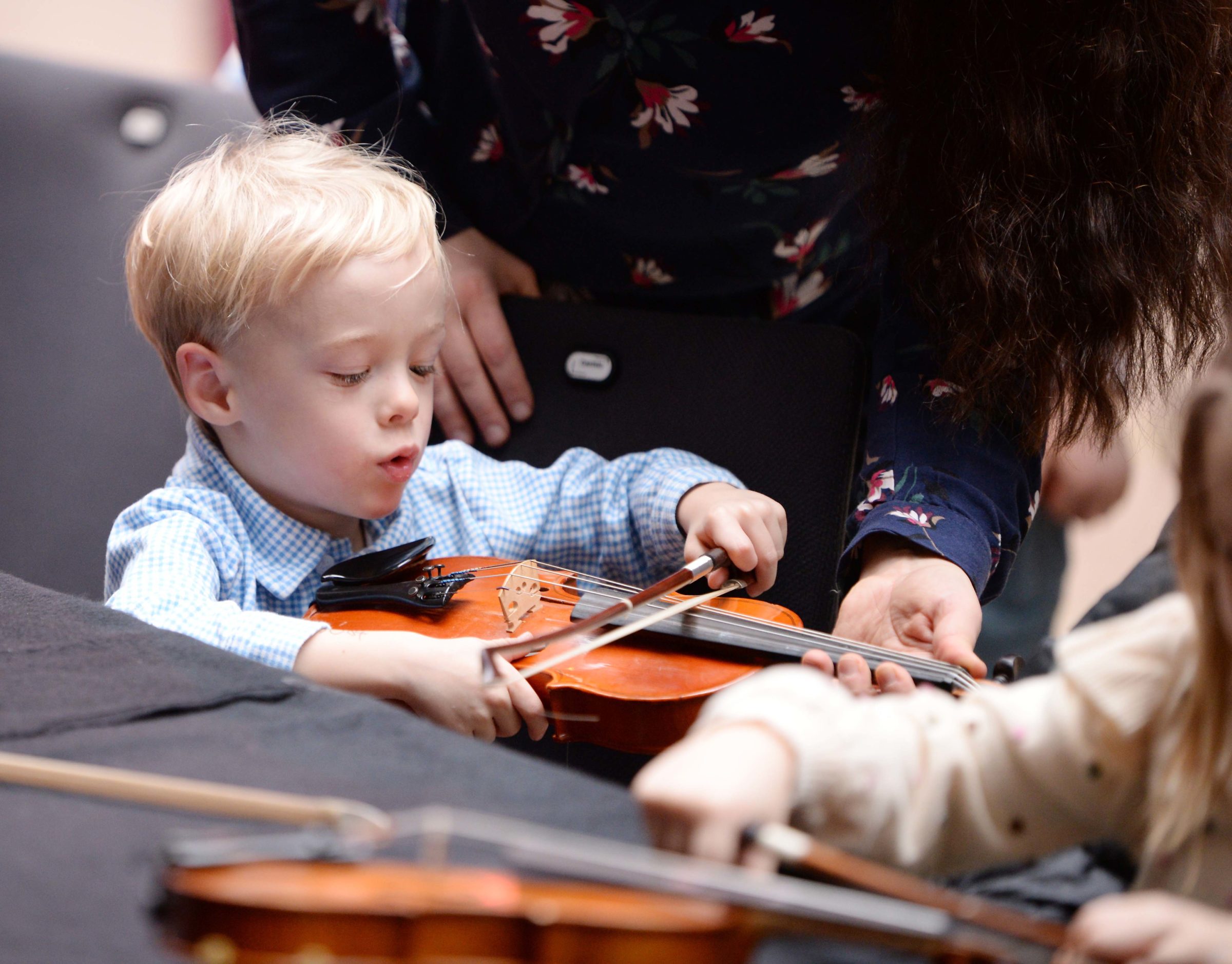 Ein Kind streicht auf einer Geige.