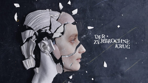 Ein Gesicht von der Seite. Es ist aus Gips und auf dem schwarzen Boden zersprungen.