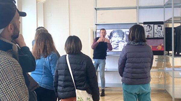 Foto Kunstgespräch in DGS in der Rathausgalerie: Ein Museum Signer beschreibt die Ausstellung für Besucher*innen, die sich um ihn versammeln