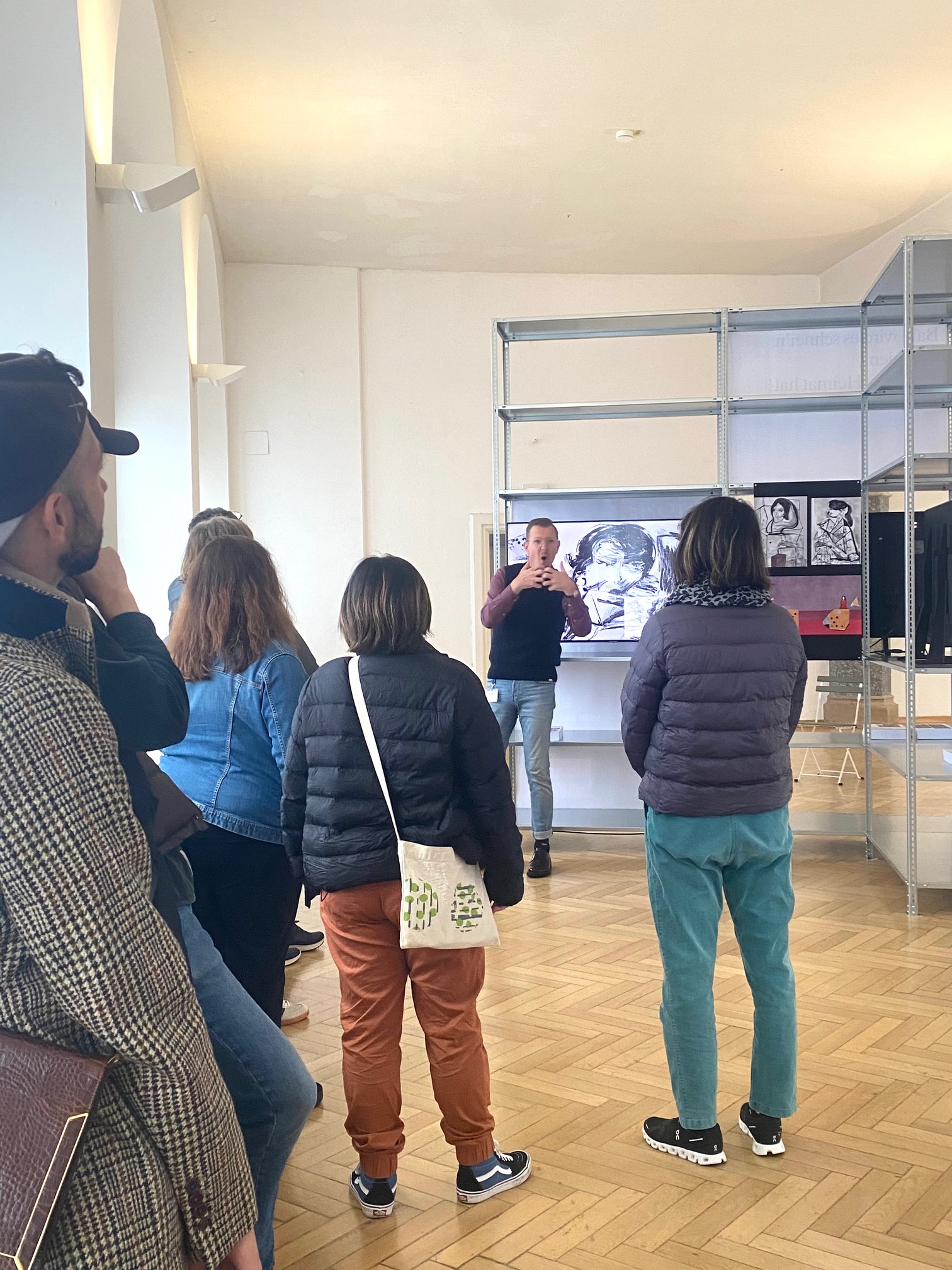 Foto Kunstgespräch in DGS in der Rathausgalerie: Ein Museum Signer beschreibt die Ausstellung für Besucher*innen, die sich um ihn versammeln